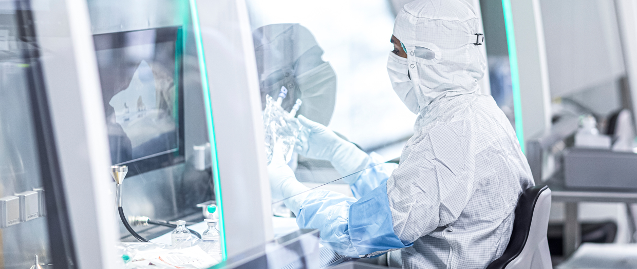 Mitarbeiter in Vollmontur an einer Werkbank im Reinraumlabor der ABF-Pharmazie